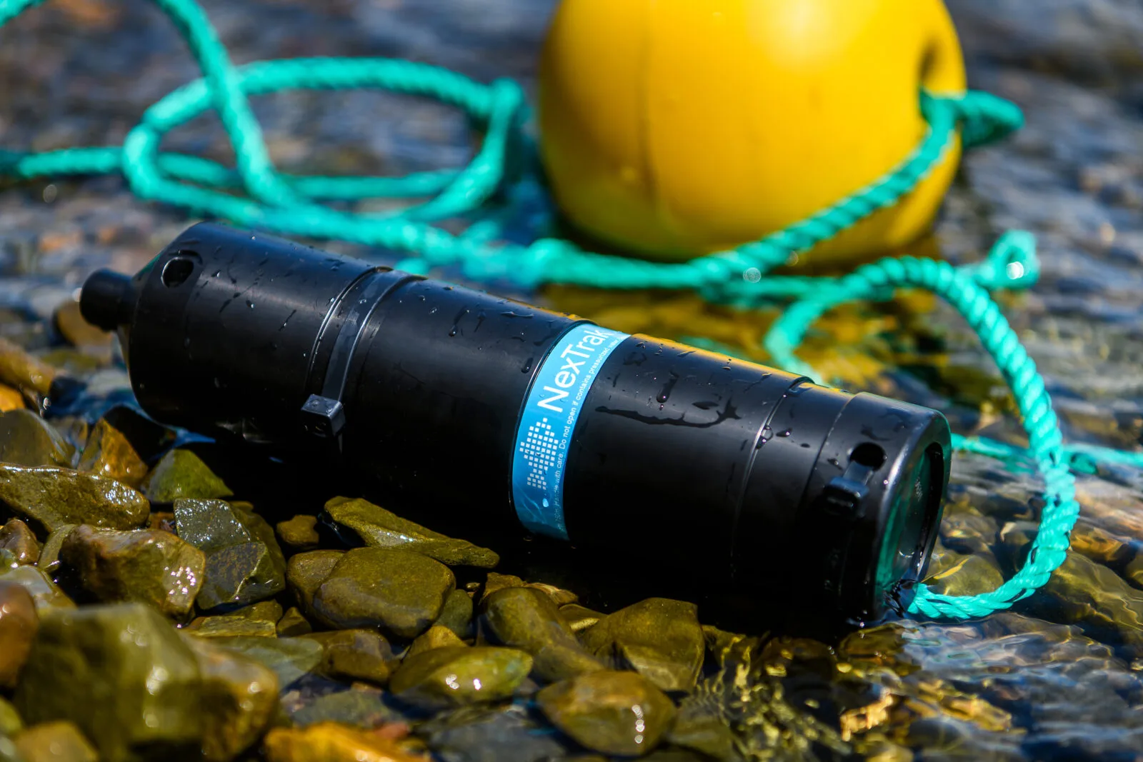 a NexTrak R1 Receiver lying on some stones by the sea