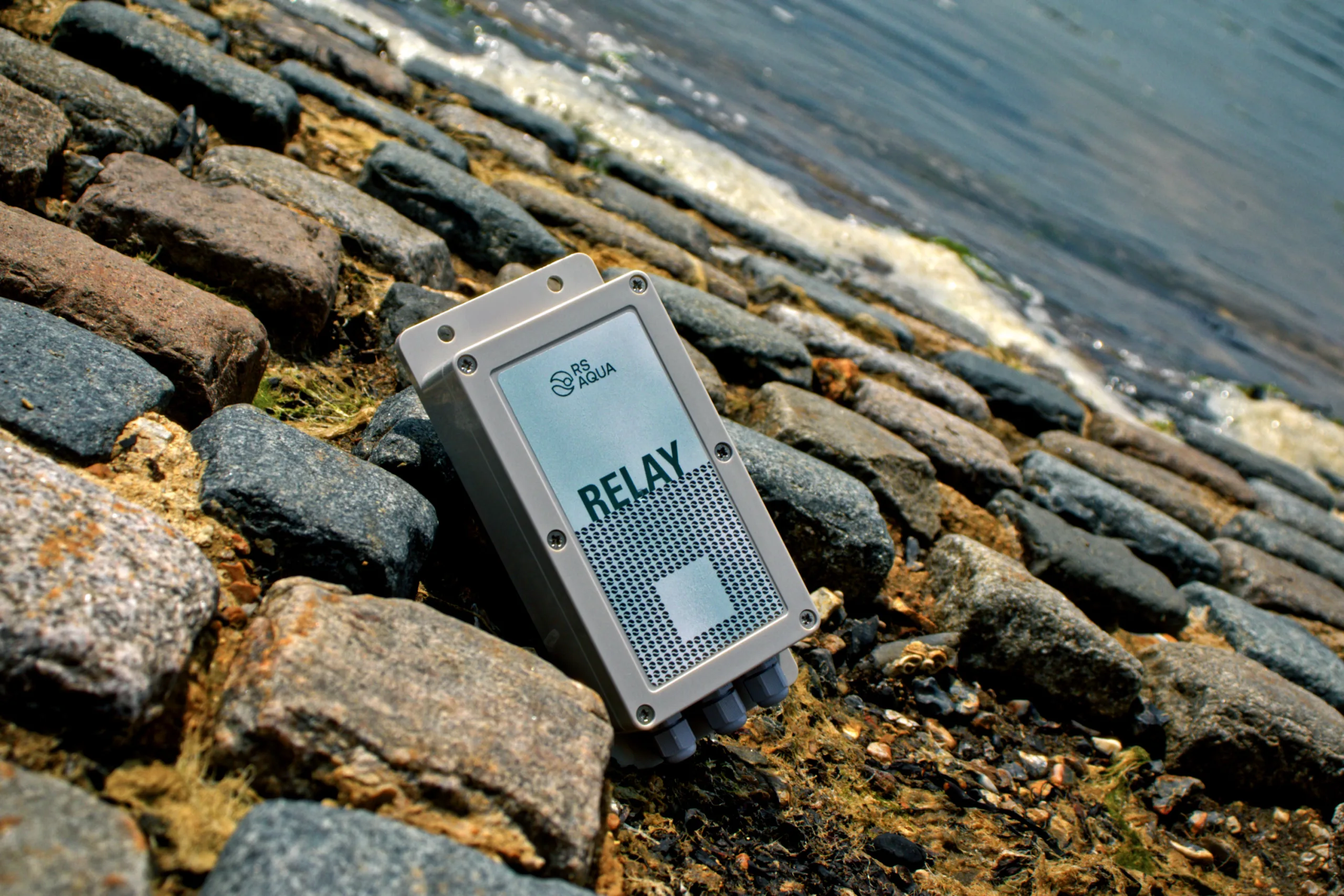 Relay smart switch resting between stones on a slipway